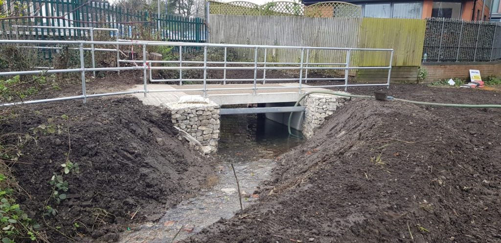 Installed precast concrete culvert with stone abutments and galvanised handrails forming a small footbridge by WCCP Devon