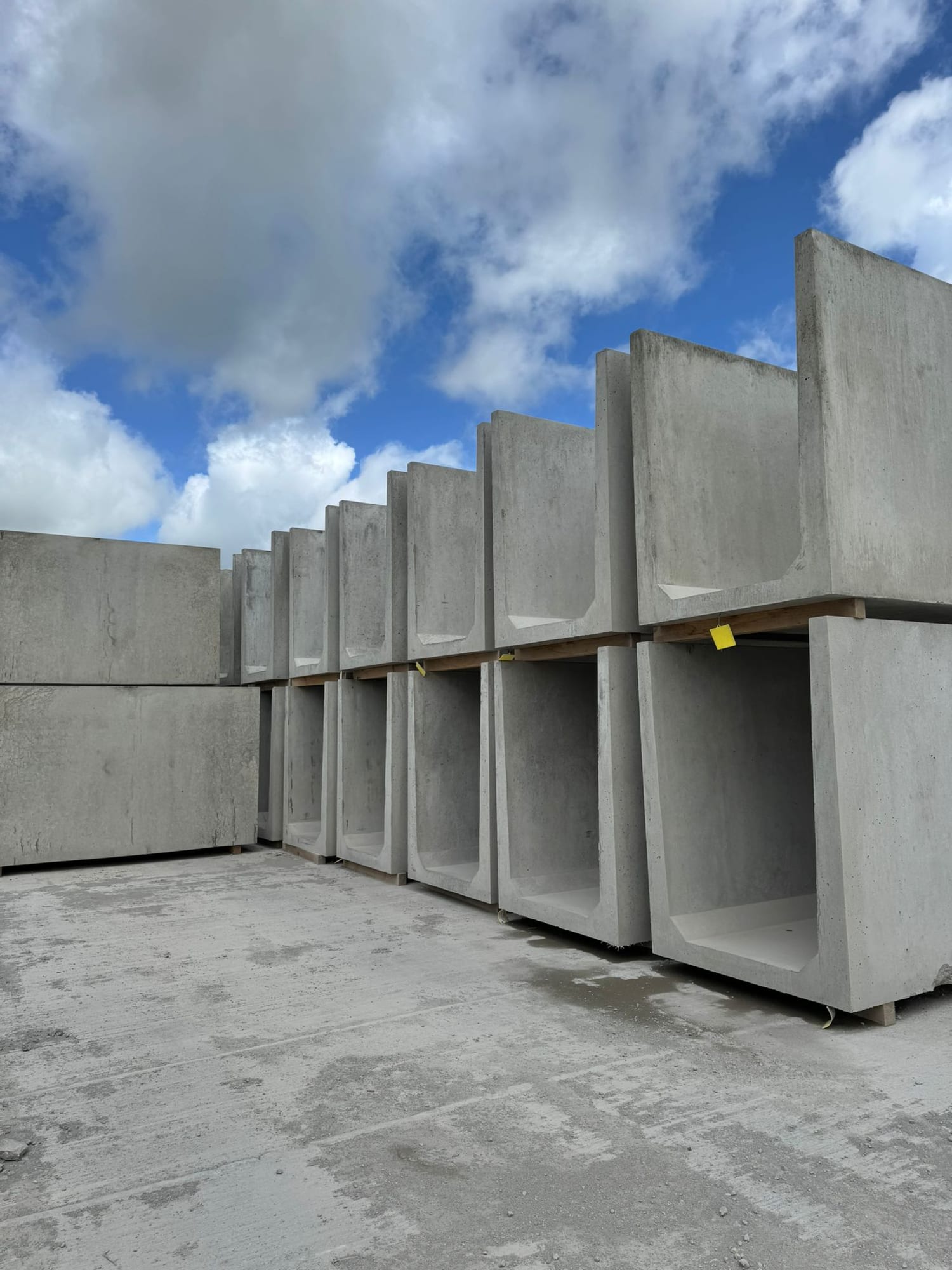 Rows of large precast concrete box culvert sections standing upright in the WCCP yard at Chilsworthy, Devon, with dramatic sky above
