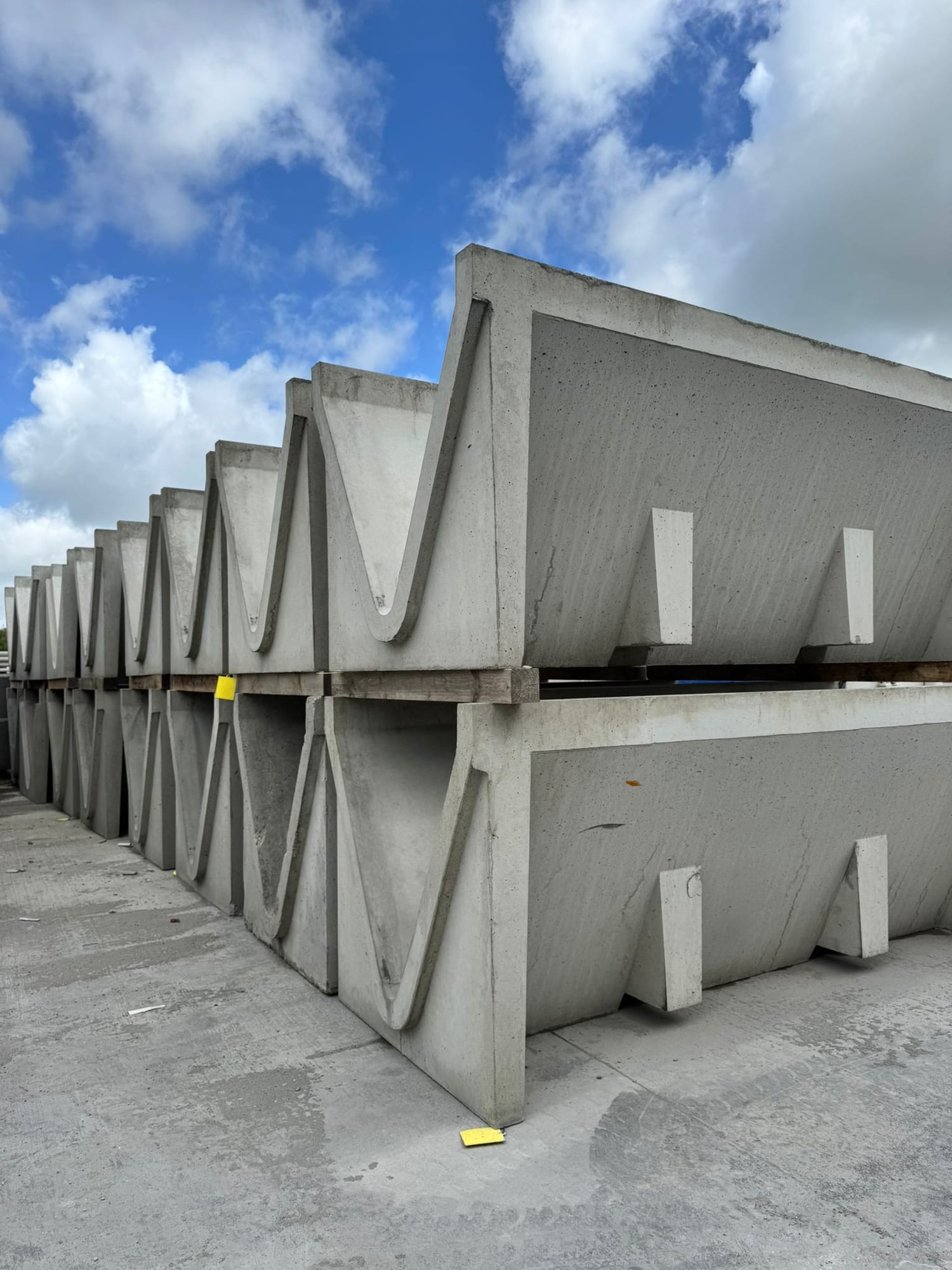 Row of V-shaped precast concrete cattle feed troughs with triangular cross-section stacked on pallets at the WCCP yard, Chilsworthy, Devon