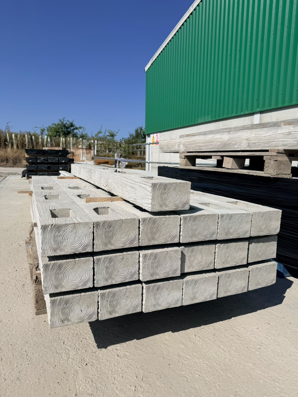 Close-up of precast concrete fence post ends showing the wood-grain finish and mortice slots for rails