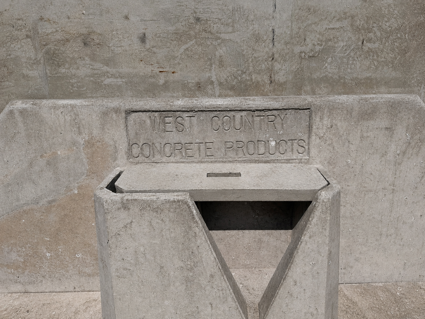 Close-up of the cast-in "West Country Concrete Products" branding stamp on a precast concrete water trough