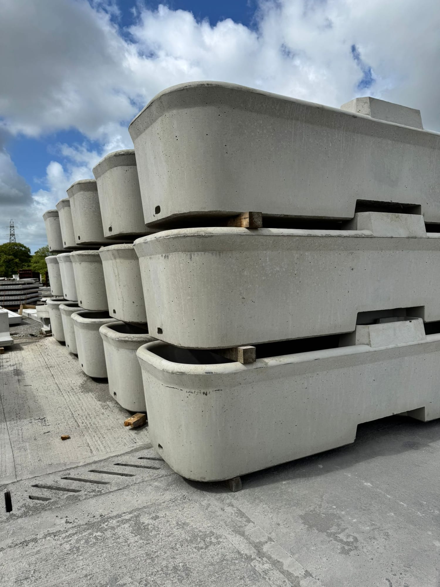 Close-up side view of precast concrete cattle drinking troughs showing rounded end profile, stacked three high at WCCP Devon
